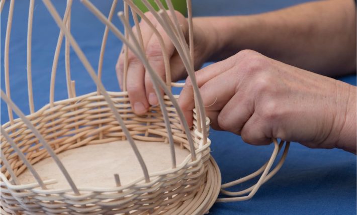 Hände flechten einen Weidenkorb als Bild für das Leistungsfeld Geriatrie